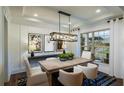 A dining room featuring a wood table, white chairs, modern light fixture, and large picture window at 264 Rockledge Sw Bnd, Powder Springs, GA 30127