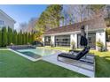 Daytime view of backyard pool area featuring lounge chairs and a small waterfall feature at 7165 Cordery Rd, Cumming, GA 30040