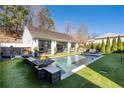 Daytime view of the backyard pool area with outdoor seating, fire bowls and pool house with glass doors at 7165 Cordery Rd, Cumming, GA 30040
