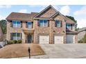 Attractive two-story brick home featuring a three-car garage, manicured lawn, and traditional curb appeal at 4869 Locherby Dr, Fairburn, GA 30213