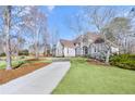 Lovely two-story house featuring mature trees, a sprawling lawn, and a curved driveway at 7015 Polo Dr, Cumming, GA 30040