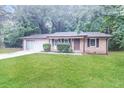 Well-maintained single-story brick home with an attached garage and a lush green lawn at 5411 Louis Xiv Ln, Atlanta, GA 30349