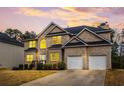 Inviting two-story brick home with a two-car garage, lush lawn, and attractive curb appeal at dusk at 4526 Warren Mill Trl, Ellenwood, GA 30294