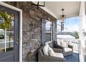 Cozy front porch with stone exterior, seating, and stylish lighting, creating an inviting entrance at 213 Augusta Walk, Canton, GA 30114