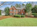 Charming brick home with lush lawn, showcasing classic architecture and mature trees at 1558 Amberwood Creek Nw Dr, Kennesaw, GA 30152