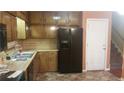 Kitchen featuring wood cabinets, black appliances, stainless steel sink, and access to the stairway at 7356 Caribou Trl, Riverdale, GA 30296