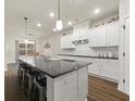 Well-lit kitchen with white cabinets, dark countertops, an island with bar stools, and hardwood floors at 2316 Ridge View Dr, Loganville, GA 30052