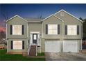 Charming split-level home featuring light-green siding, black shutters, and a convenient two-car garage at dusk at 760 Josh Ln, Lawrenceville, GA 30045