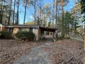 View of the back of a brick home with a covered carport and a pathway through the wooded yard at 3195 Benjamin E Mays Sw Dr, Atlanta, GA 30311