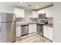 Well-lit kitchen with stainless steel appliances, granite counters, white cabinets and wood-look floors at 2631 Santa Barbara Nw Dr, Atlanta, GA 30318