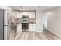 This renovated kitchen features stainless steel appliances, white cabinets, granite countertops and wood-look flooring at 2631 Santa Barbara Nw Dr, Atlanta, GA 30318