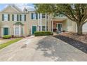 Inviting two-story townhouse with green shutters and door, complemented by a mature tree and well-maintained lawn at 112 Timber Mist Ln, Lawrenceville, GA 30045