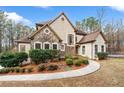 Charming home featuring a stone facade, arched windows, manicured landscaping, and a welcoming walkway at 2557 Sixes Rd, Canton, GA 30114