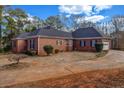 Back exterior of a red brick home featuring a two-car garage, surrounded by manicured bushes and a driveway at 1450 Brandy Shoals Se Dr, Conyers, GA 30013