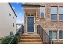 Inviting brick townhome entrance with black iron railings and a modern dark blue front door at 4447 Kerrington Ave, Sugar Hill, GA 30518