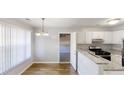 Bright kitchen and dining room area with wood floors, granite counters, white cabinets, and stainless appliances at 6299 Valdez Dr, Rex, GA 30273