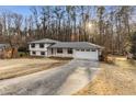 Beautifully renovated home with a white exterior, black trim, and a long driveway leading to the attached garage at 2490 Brookcliff Ne Way, Atlanta, GA 30345