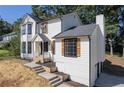 Beautiful two-story white home with black trim, stone accents, and lush greenery at 557 Old Friar Tuck Ln, Stone Mountain, GA 30087