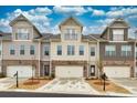 Street view of townhomes featuring neutral siding, stone accents, individual garages, and charming balconies under a partly cloudy sky at 2020 Manor Pointe Dr, Cumming, GA 30041