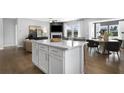Modern kitchen island with quartz countertops, white cabinets, and hardwood floors, open to living and dining areas at 189 Park Ln, Fairburn, GA 30213