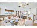 Bright, open-concept living room with modern lighting and neutral decor flows into kitchen at 5773 Tillman Way, Powder Springs, GA 30127