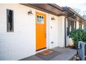 Inviting home exterior featuring a bright orange front door, white brick, and stylish light fixtures at 2411 Fair Ln, Decatur, GA 30032