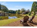 Beautiful home backyard features a serene lake view with chairs for relaxation at 5080 Riverlake Dr, Peachtree Corners, GA 30097