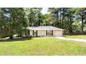 Exterior view of home showcasing its well-maintained lawn and setting among mature trees at 8169 Kendrick Rd, Jonesboro, GA 30238