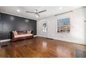 Living room featuring hardwood floors, modern ceiling fan, and a decorative black accent wall at 1547 Melrose Sw Dr, Atlanta, GA 30310