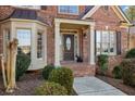 A close-up of the home's entrance featuring a brick walkway, manicured bushes, and a decorative front door at 845 Saint Marks Walk, Suwanee, GA 30024