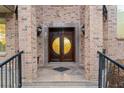 Grand double front door with decorative glass, set in a brick facade with elegant sconces and iron railings at 2146 Greensward Ne Dr, Atlanta, GA 30345