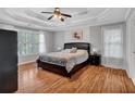 A cozy main bedroom boasts a tray ceiling, hardwood floors, and large windows with plantation shutters at 308 Lismore Ter, Woodstock, GA 30189