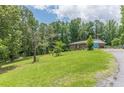Scenic view of a brick home with an attached garage, set on a large lot with mature trees and lush lawn at 5255 Post Rd, Winston, GA 30187