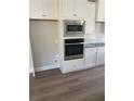 White kitchen features stainless appliances, a built-in microwave, and a decorative backsplash at 3076 Zodiac Ct, Lawrenceville, GA 30044