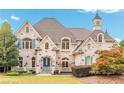 A charming brick home with manicured landscaping, blue shutters and a welcoming blue front door at 165 Ansley Way, Roswell, GA 30075