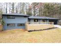 A gray painted brick home features black trim, a new wood deck, and modern curb appeal at 1120 Taliwa Ne Trl, Marietta, GA 30068