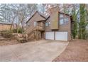 Charming home featuring a two-car garage, a wooded yard, and stairs to the front entrance at 123 Williamsburg Ln, Woodstock, GA 30189