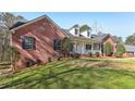 A charming home showcasing the brick facade, complemented by a covered front porch and mature trees at 211 Garden W Walk, Hampton, GA 30228