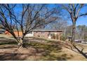 View of a brick home on a sloped lot with mature trees at 3140 Westmart Ln, Atlanta, GA 30340