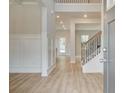 Inviting entryway with light wood floors, staircase with iron spindles, and decorative wall paneling at 308 Moab Ct, Stockbridge, GA 30281