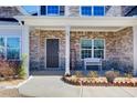 Inviting front porch with brick accents and a cozy bench, creating a welcoming entrance to the home at 12 Saint Georges Pl, Sharpsburg, GA 30277