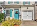 Close up of townhome with teal door, white garage door, and colorful flower wreath at 820 Ash St, Canton, GA 30114