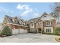 An impressive brick home showcases a three-car garage and stone accents on the facade at 5284 Vernon Springs Trl, Sandy Springs, GA 30327
