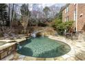 Backyard pool area featuring a waterfall, slide, stone patio, and a built-in grill, perfect for outdoor entertaining at 5284 Vernon Springs Trl, Sandy Springs, GA 30327