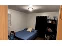 Simple bedroom with a blue bedspread, a compact shelf, and a window at 10143 Settlers Grove Ne Rd, Covington, GA 30014