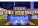 Luxury backyard pool with submerged seating, outdoor fireplaces, and lush landscaping at night at 3451 Paces Valley Nw Rd, Atlanta, GA 30327