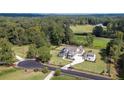 Aerial view of a sprawling property showcasing a modern home, lush green landscape, and surrounding woodlands at 2497 Sugar Pike Rd, Canton, GA 30115