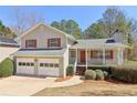 Traditional home featuring red shutters, a front porch, and an attached two-car garage at 5537 Riverside Dr, Sugar Hill, GA 30518