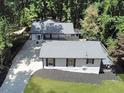 An aerial view of a single-story house showing its backyard, driveway, and surrounded by lush trees at 7360 Fields Dr, Cumming, GA 30041