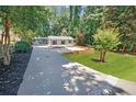 Inviting single-story house with a long driveway surrounded by lush greenery and well maintained lawn at 7360 Fields Dr, Cumming, GA 30041